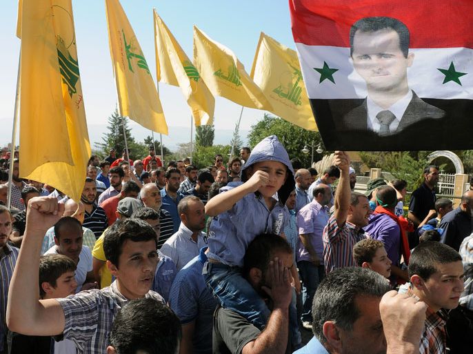 Supporters of Hezbollah shout anti-US slogans as they hold Hezbollah flags and a Syrian flag depicting Syrian President Bashar al-Assad (R) on it during a mass rally to denounce an anti-Islam US-made film, in Baalbeck at Bekaa Valley, Lebanon, 21 September 2012. Muslims across many countries used Friday prayers to rally and protest against a US-made anti-Islam video and French cartoons mocking the prophet Muhammad. EPA/WAEL HAMZEH