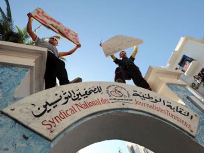 Tunisian Journalists holding placards protest as they stand on top of the entrance arch to the National Union of Tunisian Journalist building during a strike on October 17, 2012 in the capital Tunis, after months of rising tensions with the Islamist-led government, which is accused of curbing press freedom and seeking to control public media groups. AFP PHOTO / FETHI BELAID