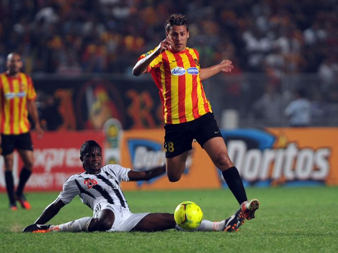 Esperance of Tunisia striker Youssef Msakni (R) leaps over Democratic Republic of Congo TP Mazembe's of Ilongo Ngasanya (C) on October 20, 2012 during a CAF Champions League semi-final football match at the Rades Olympic stadium near Tunis. AFP PHOTO / FETHI BELAID