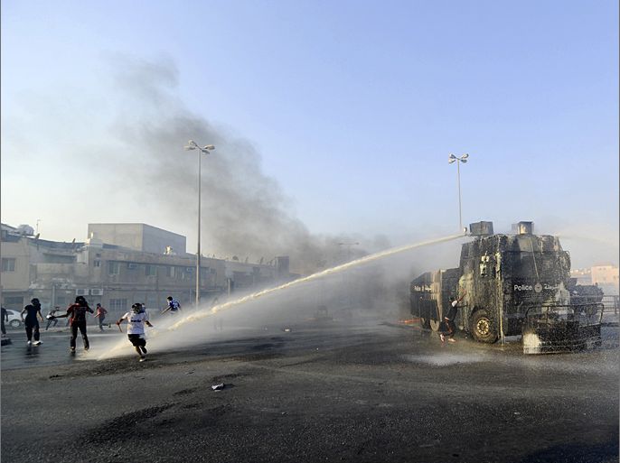 Anti-government protesters take cover from a water cannon tanker as they march towards Pearl Square after visiting the grave of Mohammed Ali Moshaima in the village of Jidhafs, west of Manama, October 5, 2012. Moshaima, who was sentenced to 7 years in jail in a protest case at the Bahrain Financial Harbour, died on October 2, from sickle-cell disease, Bahrain authorities said. REUTERS/Stringer (BAHRAIN - Tags: CIVIL UNREST POLITICS)