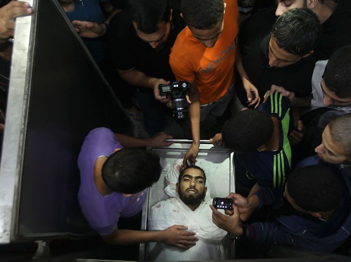epa03444275 Palestinians look at the body of Hamas militant Ismail Altli in the Kamal Edwan hospital morgue in the Jabaliya Refugee Camp, in the northern Gaza Strip, 24 October 2012. An Israeli air strike on 23 October killed two militants from Hamas and injured another three. EPA/ALI ALI
