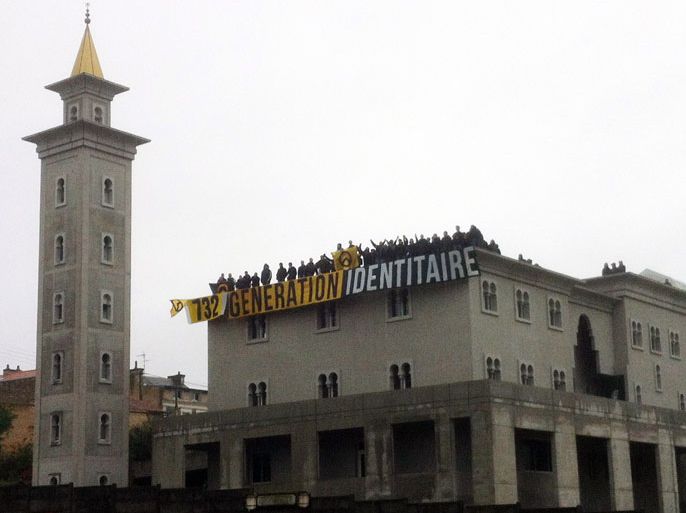 A group of far right militants deploy a banner with the name of their movement "Generation Identitaire" as they stand on the roof of the mosque in Poitiers on October 20, 2012. Police evacuated some 70 miliants and arrested three of them