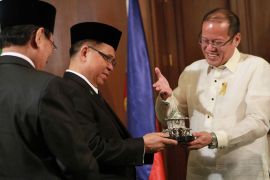 epa03433596 Moro Islamic Liberation Front (MILF) Chair Murad Ebrahim (L) receives a 'Bayanihan' figurine from Philippine President Benigno Aquino III (R) during a meeting at the presidential palace in Manila, Philippines, 15 October 2012. The Philippine government and MILF rebels are expected to sign a framework agreement on 15 October toward resolving a decades-old insurgency in the southern Philippines, with the agreement calling for a new autonomous entity to be called Bangsamoro, or Muslim nation. EPA/ROUELLE UMALI / POOL