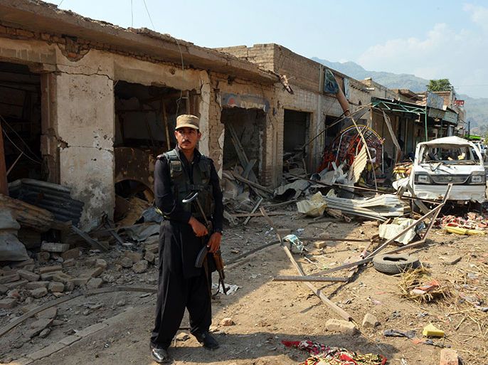 A Pakistani policeman stands guard at the site of a suicide bomb attack in Darra Adam Khel on October 13, 2012. A suicide bomber blew up a car at a crowded market in a northwestern Pakistani tribal town, killing at least 16 people and wounding 30 others, officials said. The blast ripped through the main market in Darra Adam Khel near to a local anti-insurgent peace committee office, which officials said was the target of the attack. AFP PHOTO / A. MAJEED