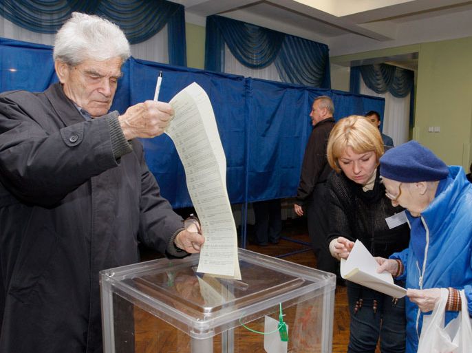 epa03449739 A Ukrainian man casts his ballot as women read their ballot papers at a polling station in Kiev, Ukraine, during the Ukrainian parliamentary elections on 28 October 2012. Voting began in Ukrainian parliamentary elections that opinion polls showed would deliver a reinvigorated opposition for the government as it faces charges of corruption and authoritarianism. Polling centres opened at 8 am (0600 GMT) and would close 12 hours later for the 36.6 million eligible voters to chose between the government side, led by President Viktor Yanukovych, and a united opposition, led by heavyweight boxing champion Vitali Klitschko and former prime minister Yulia Tymoshenko. EPA/TATYANA ZENKOVICH