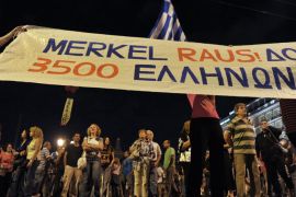Athens, -, GREECE : Anti-austerity protester hold a banner against the German Chancellor Angela Merkel during a demonstration in Athens on October 8, 2012. German Chancellor Angela Merkel will arrive in Greece on October 9 to lend support to its embattled government as a giant security operation goes into effect against new anti-austerity protests by unions. Thousands of police will create a safety zone for Merkel's meetings with conservative Prime Minister Antonis Samaras and President Carolos Papoulias, aiming to keep demonstrators at arm's length. AFP