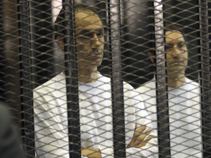 Gamal (L) and Alaa Mubarak, sons of former Egyptian President Hosni Mubarak, stand inside a cage at a courtroom in Cairo June 2, 2012. A judge sentenced Alaa and Gamal to time already served after convicting them on some corruption charges and acquitting them on others