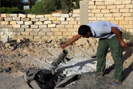 A Libyan man inspects the remains of a rocket which fell near his home in Bani Walid, about 185 kilometers southeast of Tripoli , on October 11, 2012. Deadly clashes between armed groups rocked Bani Walid on October 10, 2012, a final bastion of support of slain Libyan leader Moamer Kadhafi, as a siege of the hilltop town was partially lifted, residents said. Fighters from Bani Walid -- a town still seen by many Libyans as never truly "liberated" in last year's anti-Kadhafi revolt -- clashed with militiamen from the nearby city of Misrata who have encircled it in their search for killers of a former rebel credited with capturing the slain dictator last year. AFP PHOTO/MAHMUD TURKIA