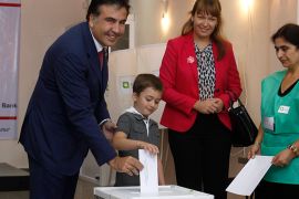 r : Georgia's President Mikheil Saakashvili (L), accompanied by his wife Sandra Roelofs (2nd R) and son Nikoloz (2nd L), casts his vote during a parliamentary election at a polling station in Tbilisi October 1, 2012. Georgians elect a parliament on Monday with tension high after a prison abuse scandal that has turned the vote into the biggest test of Saakashvili's grip on the Caucasus Mountain nation in nearly a decade in power. REUTERS/David Mdzinarishvili (GEORGIA - Tags: POLITICS ELECTIONS)