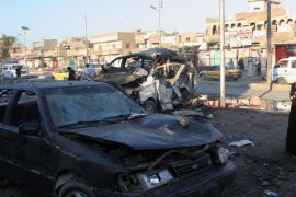An Iraqi woman looks at the wreckage of destroyed cars on October 28, 2012, at the site of a car bomb, which was exploded the day before in Baghdad's Sadr city. Attacks mostly targeting Shiite Muslims during the Eid al-Adha