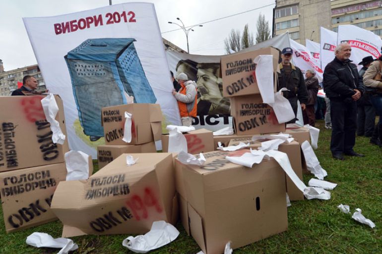 SUP-789 - Kiev, -, UKRAINE : Protesters stand next to boxes symbolizing ballot boxes during a rally of the opposition in front of the central election commission in Kiev on November 5, 2012. Thousands of Ukrainians massed in central Kiev on November 5 to protest against alleged fraud in parliamentary elections won by the ruling party as the opposition threatened not to recognise the new legislature. At least 2,000 opposition supporters carrying Ukrainian flags gathered outside the headquarters of the central election commission amid a heavy presence of elite Berkut anti-riot police, an AFP correspondent said. AFP PHOTO/ SERGEI SUPINSKY