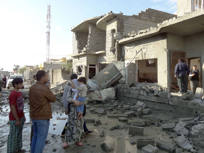 ‪أسرة عراقية بكركوك أمام الحطام الناتج عن أحد التفجيرات‬  (الفرنسية)