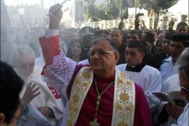 The Latin Patriarch of Jerusalem Fuad Twal (C), the head of the Roman Catholic Church in the Holy Land, sprinkles holy water outside the Church of the Nativity as Christians gather for Christmas celebrations in the West Bank city of Bethlehem, on December 24, 2012. Thousands of Palestinians and tourists flocked into the West Bank city of Bethlehem to mark Christmas in the "little town" where many believe Jesus Christ was born.  AFP PHOTO/MUSA AL-SHAER