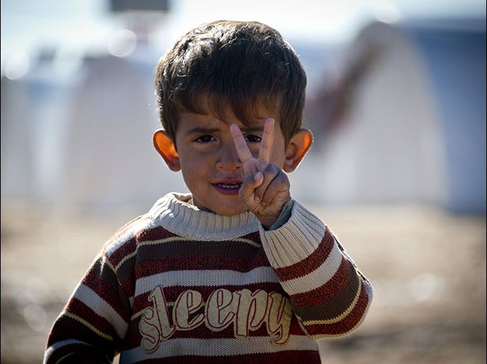 Standing in front of a row of plastic tents a young boy flashes the V-sign in a refugee camp on the border between Syria and Turkey near the northern city of Azaz on December 5, 2012. The internally displaced faced further misery as heavy rain was followed by a drop in temperatures. The United Nations estimated late October that more than 2.5 million people have been affected by the fighting in Syria. There are more than 348,000 Syrian refugees registered in neighbouring countries, but many more are unregistered. AFP PHOTO / ODD ANDERSEN