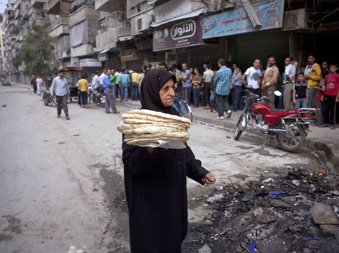 epa03429829 A picture made available on 12 October shows a Syrian woman returning home after picking up bread in a bread line in Aleppo, Syria, 11 October 2012. Places such as bread lines, hospitals and schools, where women, children and the elderly take refuge are daily targets for Syrian Army snipers and artillery shelling. About 90 percent of the wounded and the dead are civilians. Syrian rebels claim to have completely cut off the highway linking Damascus with Aleppo, preventing government troops to reach the city. EPA/MAYSUN