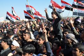 متظاهرون يرفعون الأعلام العراقية