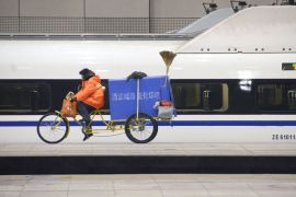 Beijing, -, CHINA : A cleaner rides a tricycle past a high-speed train running from the Beijing to Guangzhou, south China's Guangdong province, at the Beijing west railway station in Beijing on December 26, 2012. China on December 26 started service on the world's longest high-speed rail route, the latest milestone in the country's rapid and sometimes troubled super fast rail network. AFP PHOTO / WANG ZHAO