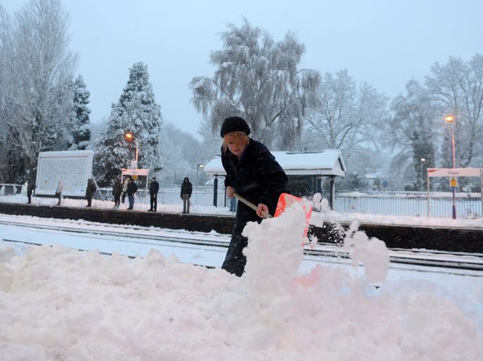 epa01980965 A female railway worker tries to remove snow from a platform at a train station in Fleet, Hampshire, Britain 06 January 2010 while would-be commuters wait hopefully for a train on the other side. Emergency weather warnings have been issued by the Met Office for large parts of central and southern England. Some 40cm (16in) of snow has been forecast in some areas of the south as the freezing weather moves from north to south. The Met Office said Dorset, Hampshire, Oxfordshire, Berkshire and Wiltshire could see "exceptionally heavy" snow. Hundreds of schools also had to be closed as the UK entered the grip of its longest cold snap for almost 30 years. EPA/ANDY RAIN
