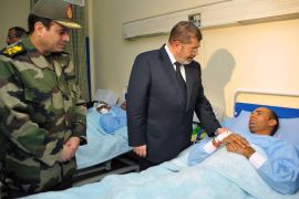 This hand out picture released by the Egyptian Presidency shows Egyptian President Mohammed Morsi (C) and Defence Minister Abdelfattah Said al-Sisi (L) visiting one of the victims of the train crash, at a military hospital in Cairo, on January 15, 2013. A train carrying military conscripts derailed southwest of Cairo on Tuesday, killing 19 people and wounding 107, the health ministry said, highlighting the country's chronic transport problems. The train was taking young recruits from south Egypt to a military camp in Cairo when two carriages went off the rails shortly after midnight in the Giza neighbourhood of Badrasheen, officials said. AFP PHOTO/ EGYPTIAN PRESIDENCY