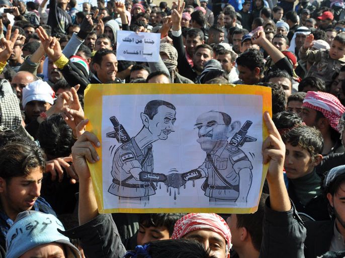 لمتظاهرين في محافظة الانباريحمل احدهم رسما كاريكاتيريا يجسد فيه المالكي وبشار الاسد