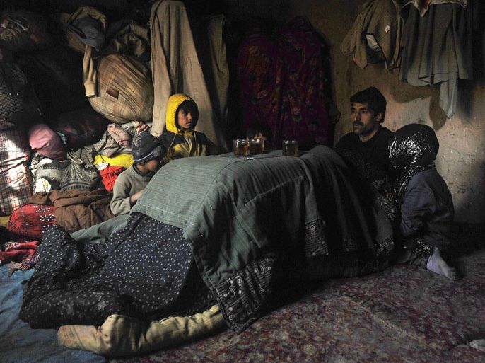 An Afghan man sits with his children amid thick blankets at a refugee camp in Herat on January 2, 2013. Hundreds of families living in makeshift shelters around the Afghan capital Kabul collected blankets, charcoal and other supplies on January 2 as authorities struggle to avoid last year's deadly winter toll. With temperatures dropping to -10 Celsius (14 Fahrenheit) at night in the city, the 35,000 refugees who live in the snow-covered camps face a battle to survive dire conditions protected only by plastic sheeting. AFP PHOTO/ Aref Karimi