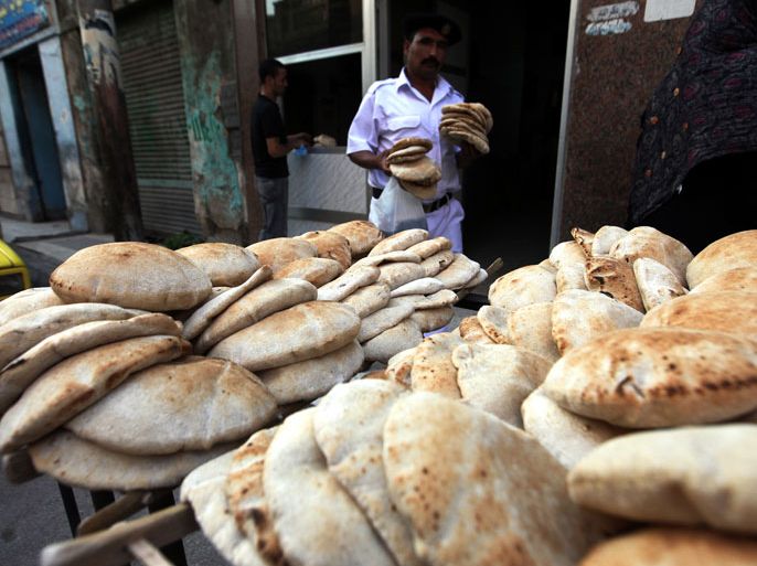 epa03425849 An Egyptian policeman carries government subsidized bread in front of a bakery in Cairo Egypt 08 October 2012. Egyptian President Mohamed Morsi vowed before his election to achieve 64 objectives during his first 100 days including tackling problems with bread shortages traffic security fuel shortages and cleanliness. EPA/KHALED ELFIQI
