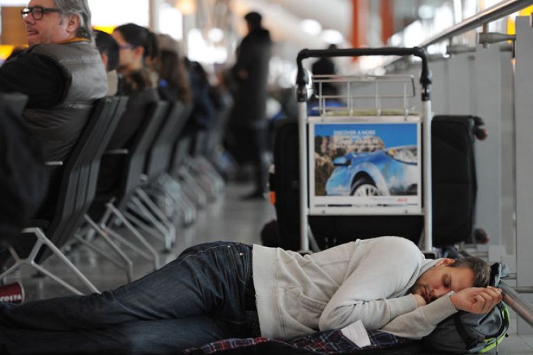 epa03544259 A passenger sleeps while waiting to board a cancelled flight at Heathrow Airport's Terminal 5 in London, 19 January 2013. Over 400 flights were canceled or delayed 18 January due to sever snow storms. Thousands of passengers were forced to sleep at the airport. EPA/ANDY RAIN