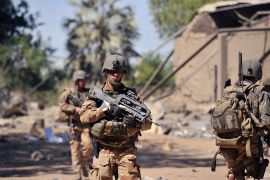 French soldiers walk past Malian army barracks, which were taken by Islamic jihadists before being destroyed during aerial bombings, as they arrive in the Malian town of Diabaly, on January 21, 2013. French and Malian troops today recaptured the Malian towns of Diabaly and Douentza from Islamist fighters, France's defence minister said. French and Malian troops earlier today entered Diabaly, which has been the theatre of air strikes and fighting since being seized by Islamists a week ago, an AFP journalist witnessed . AFP PHOTO / ISSOUF SANOGO
