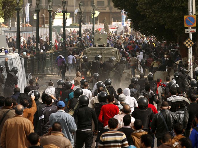 Egyptian protesters run for cover as they are chased by riot policemen during clashes near Cairo's Tahrir Square on January 27, 2013. Clashes killed at least 31 people in Egypt's Port Said as violence raged in several cities including the capital following death sentences passed on 21 football fans after a riot. AFP PHOTO/MOHAMMED ABED