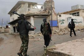 Free Syrian Army fighters walk past damaged buildings in the village of Menagh, in Aleppo's countryside, January 7, 2013. REUTERS/Mahmoud Hassano (SYRIA - Tags: CONFLICT)