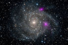 This new view of spiral galaxy IC 342, also known as Caldwell 5, obtained from NASA January 8, 2013 includes data from NASA's Nuclear Spectroscopic Telescope Array, or NuSTAR. High-energy X-ray data from NuSTAR have been translated to the color magenta, and superimposed on a visible-light view highlighting the galaxy and its star-studded arms. NuSTAR is the first orbiting telescope to take focused pictures of the cosmos in high-energy X-ray light; previous observations of this same galaxy taken at similar wavelengths blurred the entire object into one pixel. The two magenta spots are blazing black holes first detected at lower-energy X-ray wavelengths by NASA's Chandra X-ray Observatory. The black holes appear much brighter than typical stellar-mass black holes, such as those that pepper our own galaxy, yet they cannot be supermassive black holes or they would have sunk to the galaxy's center. Instead, they may be intermediate in mass, or there may be something else going on to explain their extremely energetic state. NuSTAR will help solve this puzzle.