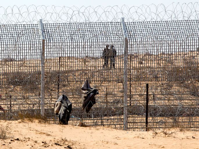 epa03427859 Egyptian soldier nearby the Israeli border fence running along the border in the Negev Desert, north of Kadesh Barnea, Israel, 10 October 2012, where pieces of clothing left by African immigrants lay tangled in the wire. Despite a drastic reduction of African immigrants, mainly from Sudan and Eritrea, crossing into Israel from Egypt, due to the border fence, Israel is building a new prison facility at Saharonim, which could house thousands of additional immigrants. EPA/JIM HOLLANDER