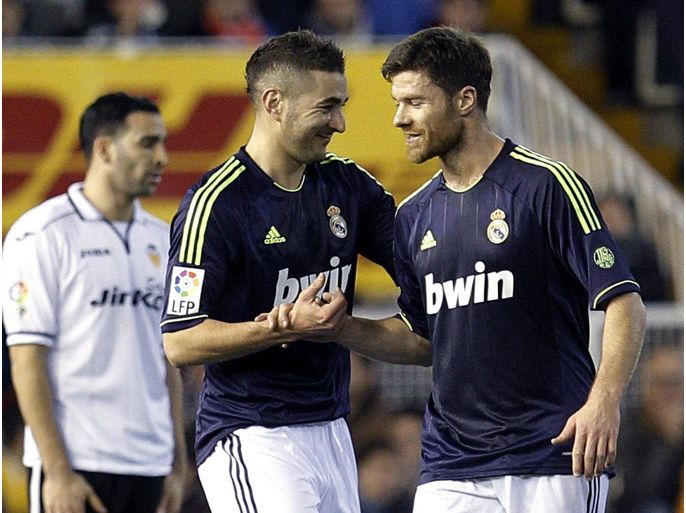 epa03552478 Real Madrid's Karim Benzema (L) celebrates with Xabi Alonso (C) after scoring the opening goal against Valencia CF during the King's Cup quarter finals second leg soccer match between Valencia and Real Madrid at the Mestalla stadium in Valencia, Spain, 23 January 2013. EPA/JUAN CARLOS CARDENAS