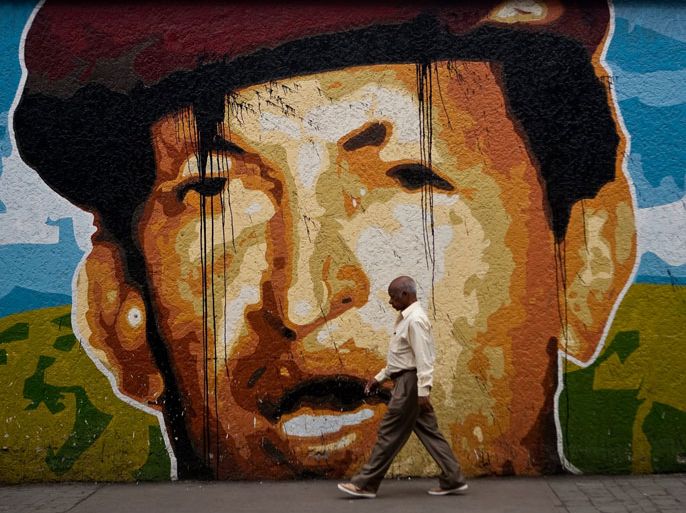 epa3 A man walks by next to a huge wall with the image of Venezuelan president Hugo Chavez in a street of Caracas, Venezuela, 12 December 2012