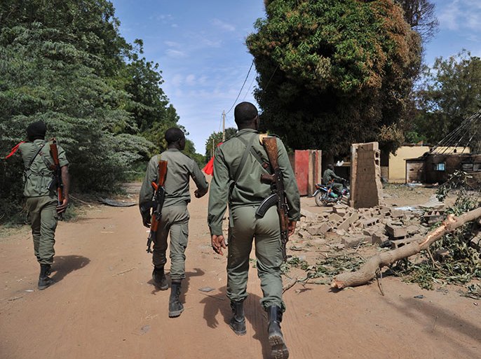 Malian soldiers walk past destroyed army barracks as they patrol in Diabaly on January 22, 2013. The EU executive today announced 20 million euros of extra humanitarian aid to help tens of thousands of Malians fleeing fighting in the nation's north and centre, its second such donation in as many months. AFP PHOTO / ISSOUF SANOGO