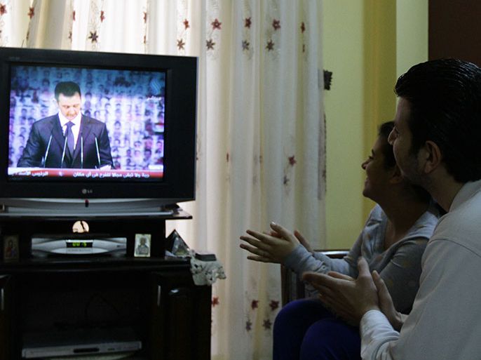 Syrian people react as they watch Syria's embattled President Bashar al-Assad making a public address on the state-run Syrian TV, on January 6, 2013 in Damascus. Bashar al-Assad in a rare speech Sunday denounced the opposition as "slaves" of the West and called for a national dialogue conference to be followed by a referendum on a national charter and parliamentary elections. AFP PHOTO / LOUAI BESHARA