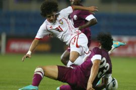 Omar Abdulrahman Ahmed (top) of United Arab Emirates tries to avoid a tackle by Sebsatian Souria of Qatar during the two teams match in the 21st Gulf Cup in Manama, on January 5,
