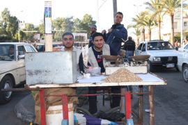 شابان في غزة يعملان على بسطة صغيرة لبيع المكسرات