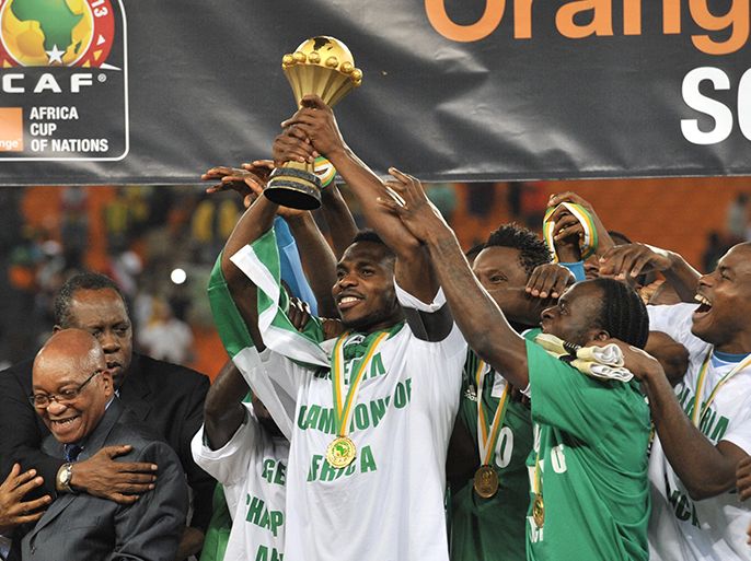 Nigeria's defender Joseph Yob (C) holds the trophy as he celebrates with teammates, South African President Jacob Zuma (2ndL) and Confederation of African Football (CAF) president Issa Hayatou after Nigeria won the 2013 African Cup of Nations final against Burkina Faso on February 10, 2013 at Soccer City stadium in Johannesburg. AFP PHOTO / ISSOUF SANOGO