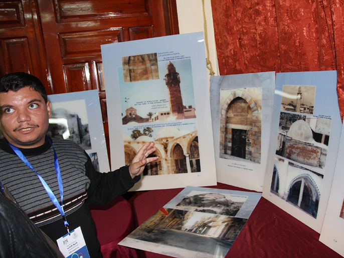 ‪أحد القائمين على المعرض يشرح للزوار عن المعالم الأثرية بالصور المعروضة‬ (الجزيرة)