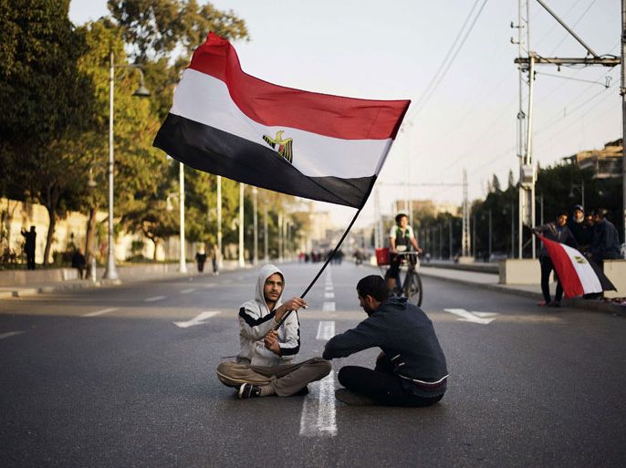 EGYPT : Egyptian anti-government protesters sit waving their national flag outside the Egyptian presidential palace in Cairo during a demonstration against Egypt's President Mohamed Morsi and the Muslim Brotherhood on February 8, 2013. Thousands took to the streets across Egypt after opposition groups called for "Friday of dignity" rallies demanding Morsi fulfill the goals of the revolt that brought him to power. AFP PHOTO/GIANLUIGI GUERCIA
