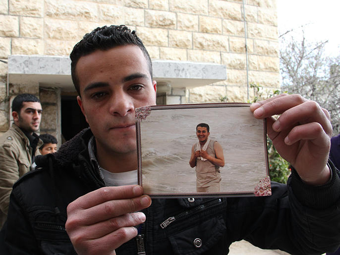‪أحد أقارب الشهيد عرفات جرادات يحمل صورته‬ (الجزيرة نت)