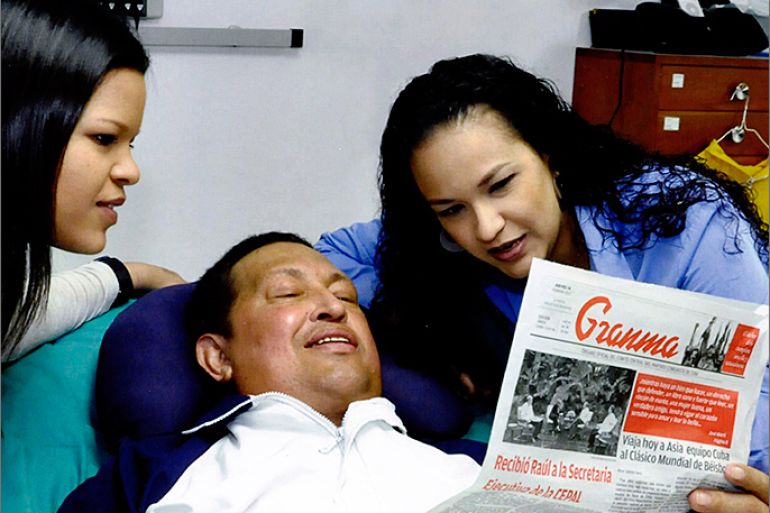 Venezuela's President Hugo Chavez holds a copy of the newspapers as his daughters, Rosa Virginia (R) and Maria watch while recovering from cancer surgery in Havana in this photograph released by the Ministry of Information on February 15, 2013. Venezuela's government published the first pictures of cancer-stricken Chavez since his operation in Cuba more than two months ago, showing him smiling while lying in bed reading a newspaper, flanked by his two daughters. The 58-year-old socialist leader had not been seen in public since the Dec. 11 surgery, his fourth operation in less than 18 months. The government said the photos were taken in Havana on February 14, 2013. REUTERS/Ministry of
