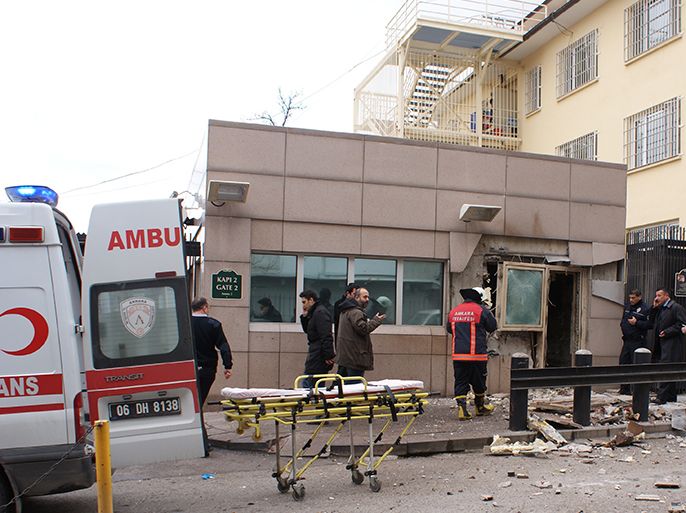 People stand outside the entrance of the US embassy in Ankara on February 1, 2013 after a blast killed two security guards and wounded several other people. It was not immediately known what caused the explosion but some media speculated it could have been a suicide bombing. The force of the blast damaged nearby buildings in the Cankaya neighbourhood where many other state institutions and embassies are also located. AFP PHOTO / IHLES NEWS AGENCY