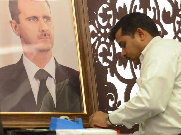 A Syrian embassy employee prepares a portrait of Syrian President Bashar al-Assad ahead of a press conference by Bouthaina Shaaban, a cabinet-level adviser to the Syrian president, at the India Islamic Centre in New Delhi on March 8, 2013. A top Syrian regime official thanked the BRICS group