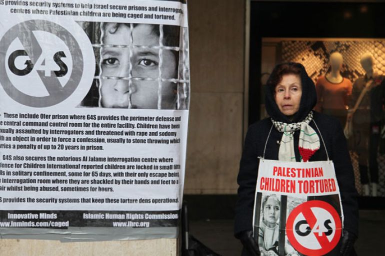متضامنة ترفع لافتة كتب عليها تعذيب الاطفال الفلسطينيين وإشارة لوقف عمل الشركة