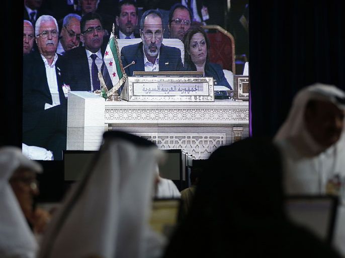Ahmed Moaz al-Khatib, head of the Syrian opposition delegation, appears on a screen as he addresses the opening of the Arab League summit in the Qatari capital Doha on March 26, 2013. Syria's main opposition group took the country's seat at the Arab League for the first time as the 22-member bloc opened the summit in Doha. Khatib, who has resigned as the head of the National Coalition but said he would address the summit, took the seat of the head of the delegation at the gathering. AFP PHOTO/KARIM SAHIB