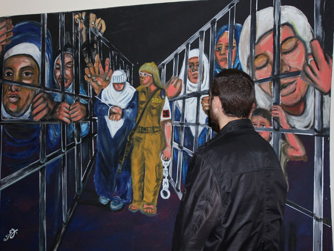 شاب غزة أمام رسم لمعاناة الأسيرات في السجون الإسرائيلية