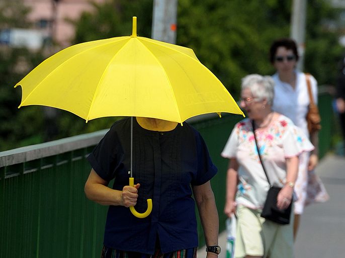 epa03272742 A woman uses an umbrella to shade herself against the burning sun during a hot day in Przemysl, Poland, 19 June 2012. Temperatures hit levels of up to 34 degrees Celsius making Podkarpacie one of the hottest regions in Poland these days, according to meteorologists. EPA/Darek Delmanowicz POLAND OUT