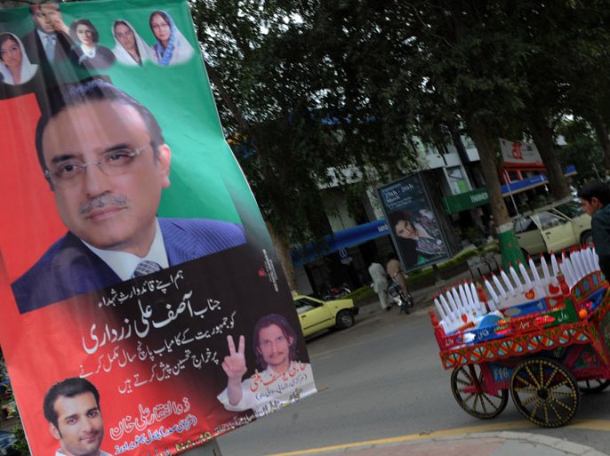 AQ2200 - Islamabad, -, PAKISTAN : An ice cream vendor passes by a banner featuring portraits of Pakistan' s President Asif Ali Zardari and Bhutto's family members along a street in Islamabad on March 20, 2013. Pakistani President Asif Ali Zardari announced on March 20 that general elections would be held on May 11, in what will mark the first democratic transition of power in the country's history. AFP PHOTO/Aamir QURESHI